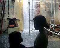 Two girls look at the water gushing from the ground of a restaurant in Jatirejo village near a 